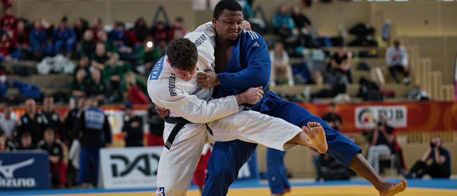 Zwei Männer welche Judo ausüben und ein weißes und blaues Kimono tragen.